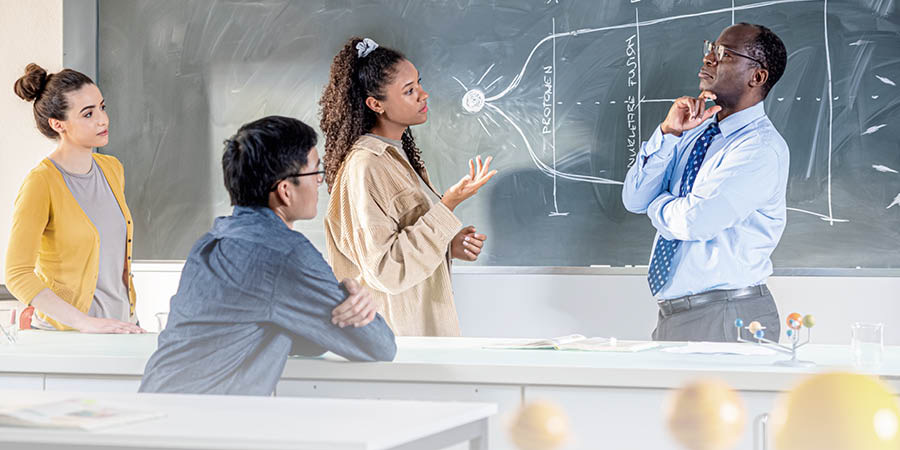 Un profesor de ciencias falando con algúns dos seus alumnos.