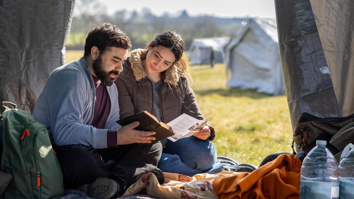 Unha parella lendo xuntos a Biblia mentres están sentados na súa tenda nun campo de refuxiados.