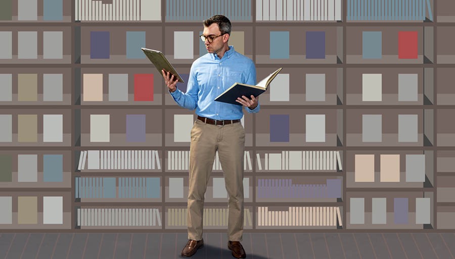 O mesmo home mirando un libro que colleu dos estantes e comparándoo coa información que encontrou no seu dispositivo electrónico