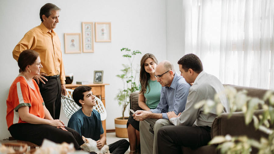 Un home moi triste sostendo unha foto mentres algúns amigos o consolan.