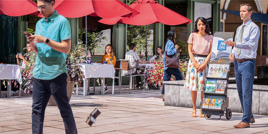 A brother at a witnessing cart noticing a man losing his wallet as a woman watches from a nearby café.
