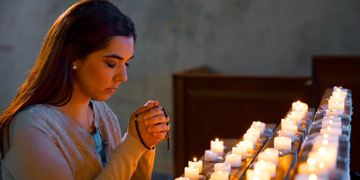 Wata mata ta kuna kyandir kuma tana amfani da rosary tana addu’a