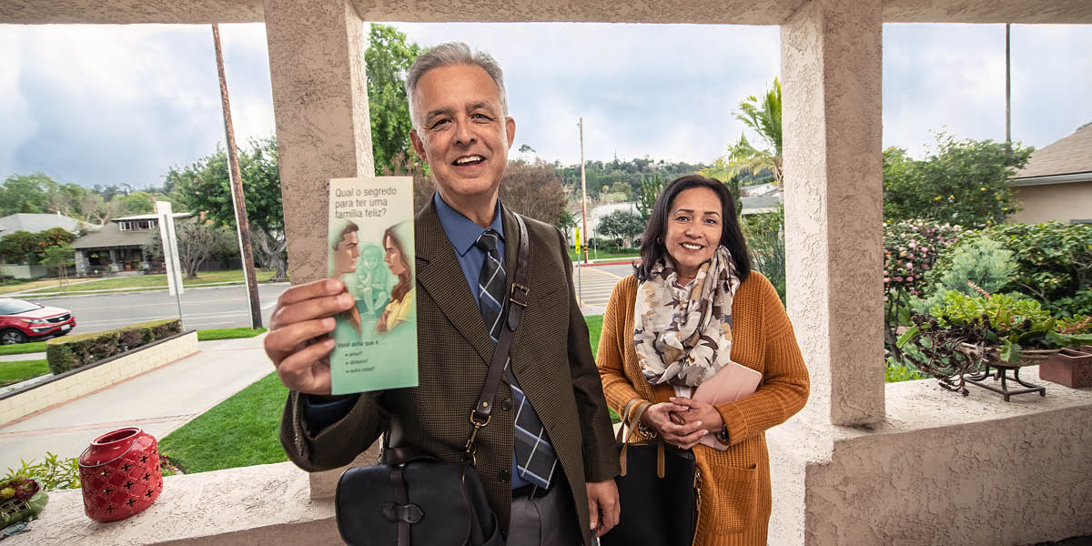 Yon frè ak yon sè k ap prezante yon moun yon feyè devan yon kamera ki gen sonèt.