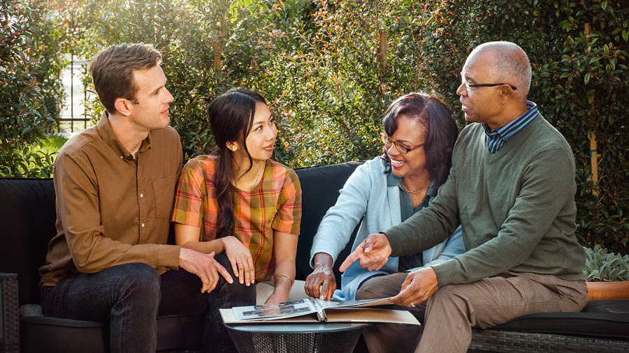 The couple talking with an older couple as they look through a photo album.