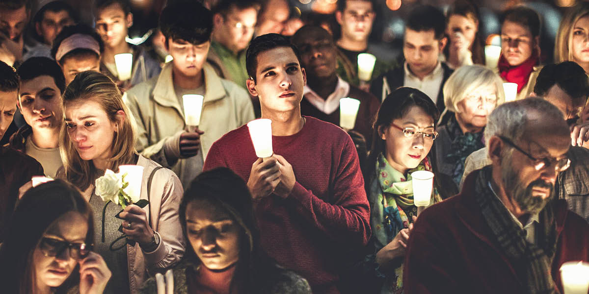 Grieving people hold candles