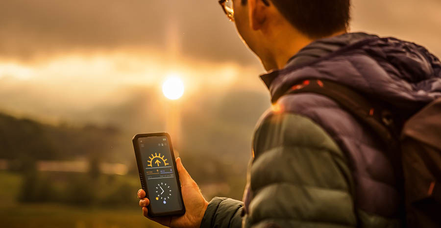 Un uomo controlla sul suo smartphone l’orario in cui tramonterà il sole.