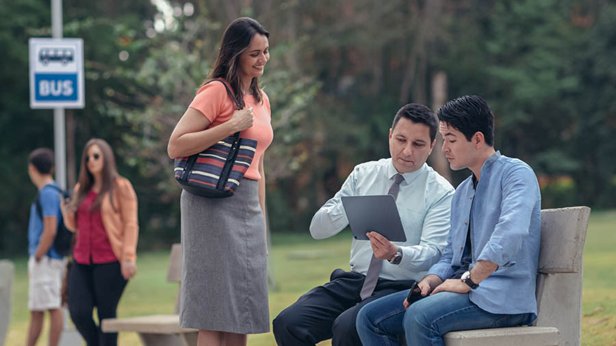 Una coppia usa l’opuscolo “Puoi vivere felice per sempre” mentre parla con un uomo a una fermata dell’autobus.