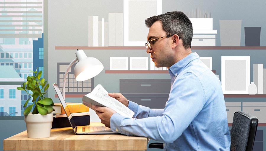 Un uomo legge la Bibbia davanti al suo computer portatile aperto