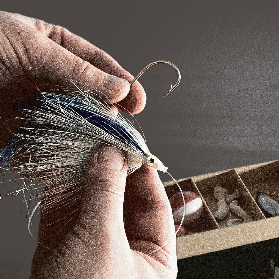 Un pescatore infila un’esca all’amo