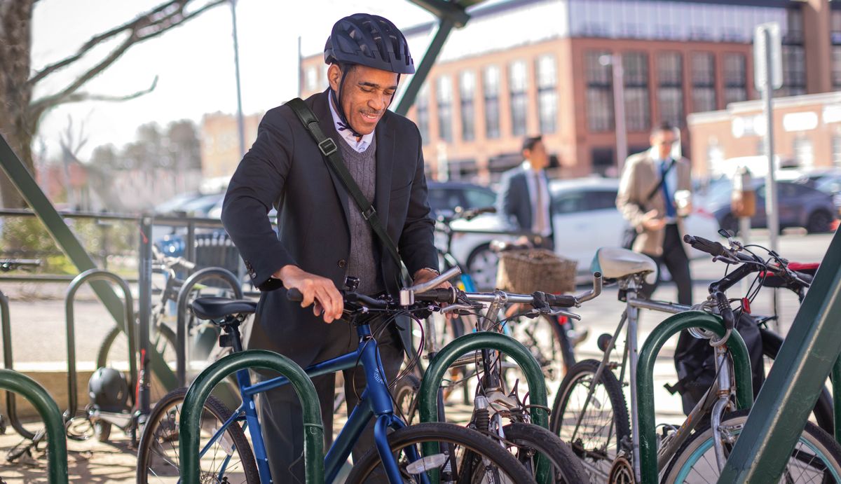 Un uomo arrivato al lavoro parcheggia la bicicletta.