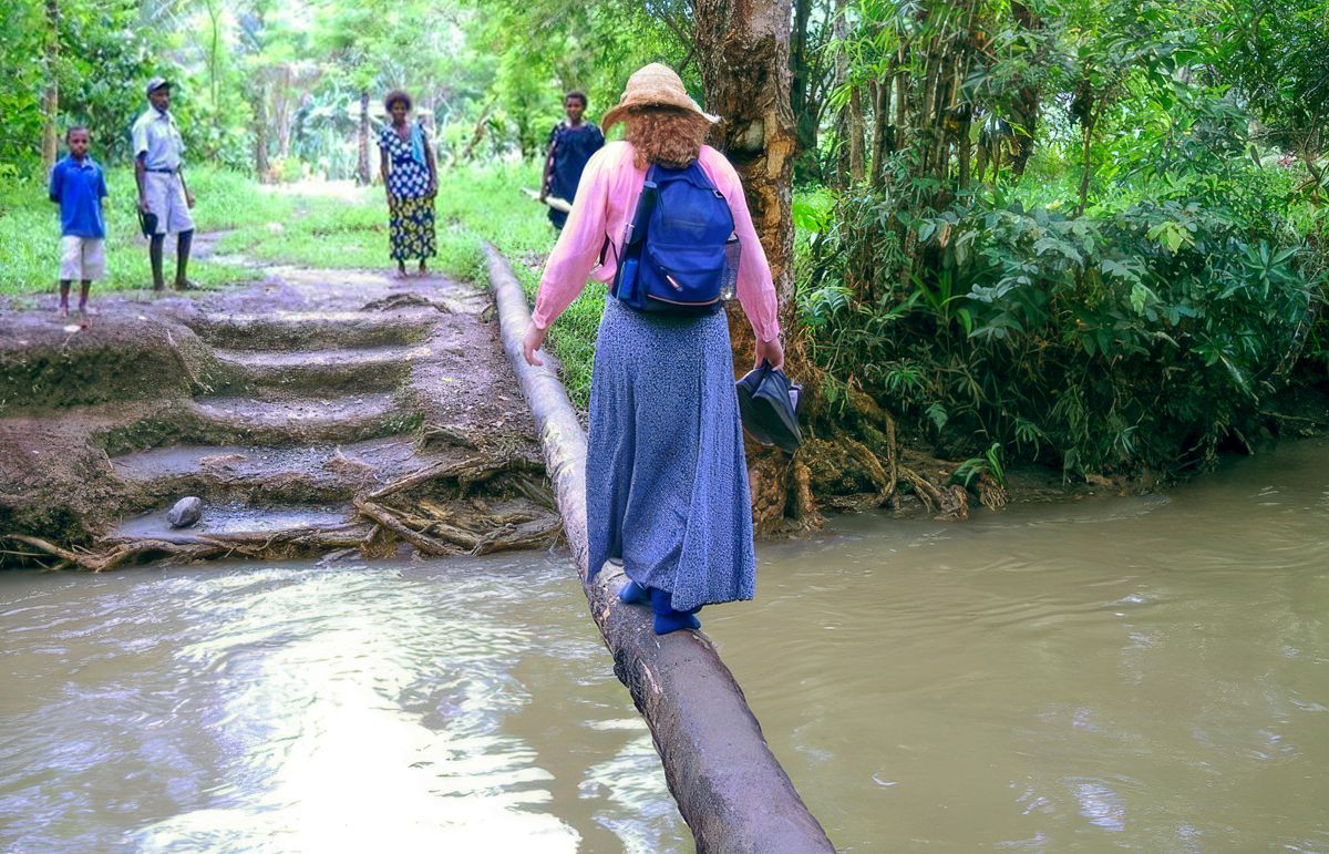 Leann cammina su un tronco stretto per attraversare un fiume.