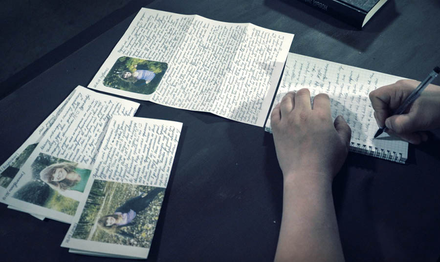 Una scena del video “Intervista al fratello Dmitrij Michajlov”. Dmitrij scrive una lettera mentre si trova in prigione. Sul tavolo ci sono varie lettere di sua moglie.