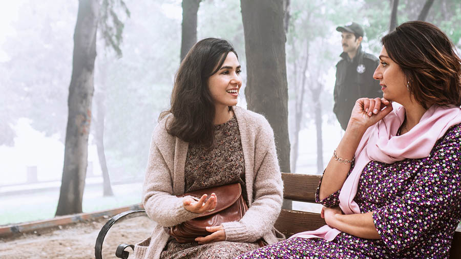 In un paese dove la nostra opera è al bando, una sorella dà testimonianza a una donna su una panchina di un parco mentre un poliziotto cammina lì vicino.