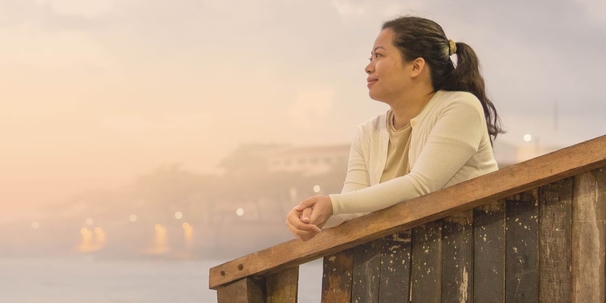 Wong wédok lagi ndelok matahari terbenam lan wajahé kétok tegar.