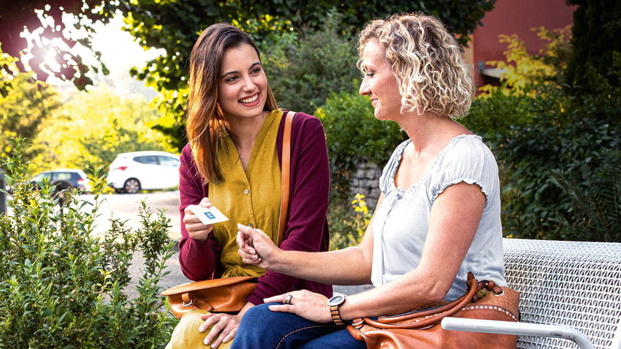 The sister preaching to a woman as they sit on a park bench.