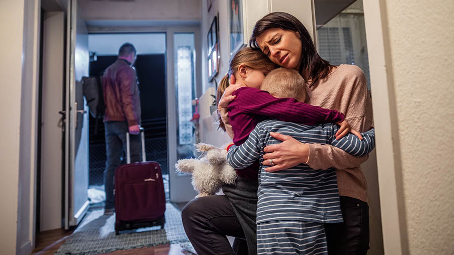 Tėvas, susikrovęs lagaminą, išeina iš namų. Mama apsikabinusi abu verkiančius vaikus.