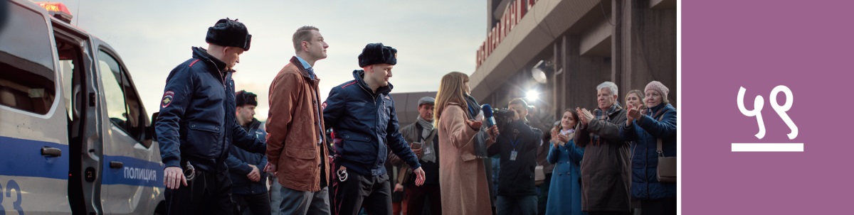 पाठ ५९. दुई जना प्रहरीले हतकडी लगाइएका साक्षी भाइलाई पत्रकारहरू र सङ्‌गी ख्रिष्टियनहरूको अगाडिबाट लैजान्छन्‌।