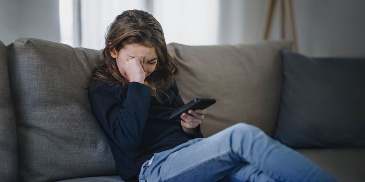 Een tienermeisje dat van streek is door wat ze op haar smartphone ziet.