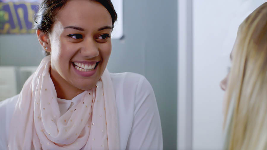 Een scène uit de video ‘Ervaar de vreugde die het geeft discipelen te maken — Aanvaard Jehovah’s hulp — Gebruik studiehulpmiddelen’. Neeta vertelt vol vreugde aan Jade wat ze tijdens haar nazoekwerk heeft gevonden.