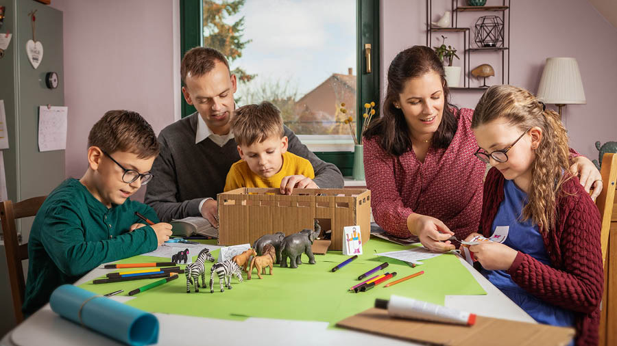 Een gezin met drie kinderen maakt een model van Noachs ark met een paar dieren.