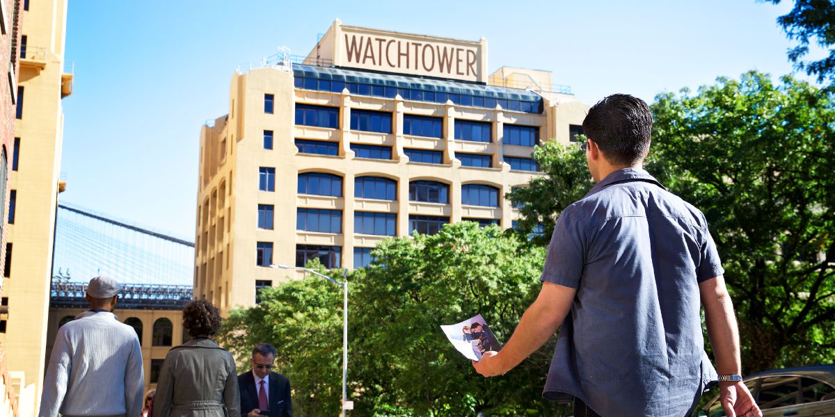 Een man die met een uitnodiging voor het open huis in de hand op weg is naar Columbia Heights 25 in Brooklyn (New York)