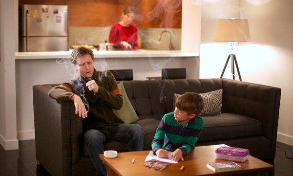 A man at home smokes and coughs, disturbing his wife and son nearby