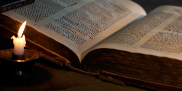 Otwarta Biblia oświetlona blaskiem świecy
