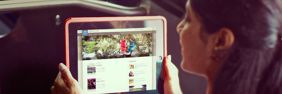 Uma mulher usando o site jw.org em seu aparelho portátil