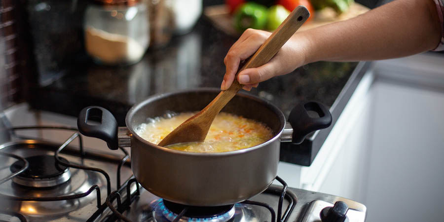 Uma mulher mexendo uma sopa que está fervendo.