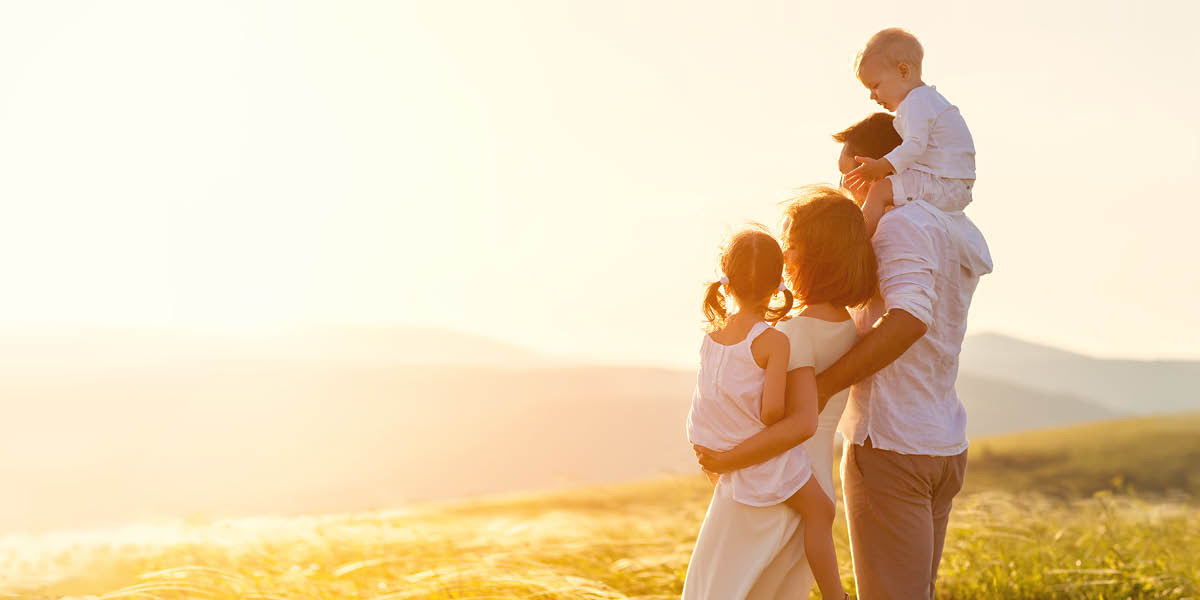 Uma família feliz olhando para o Sol no horizonte.