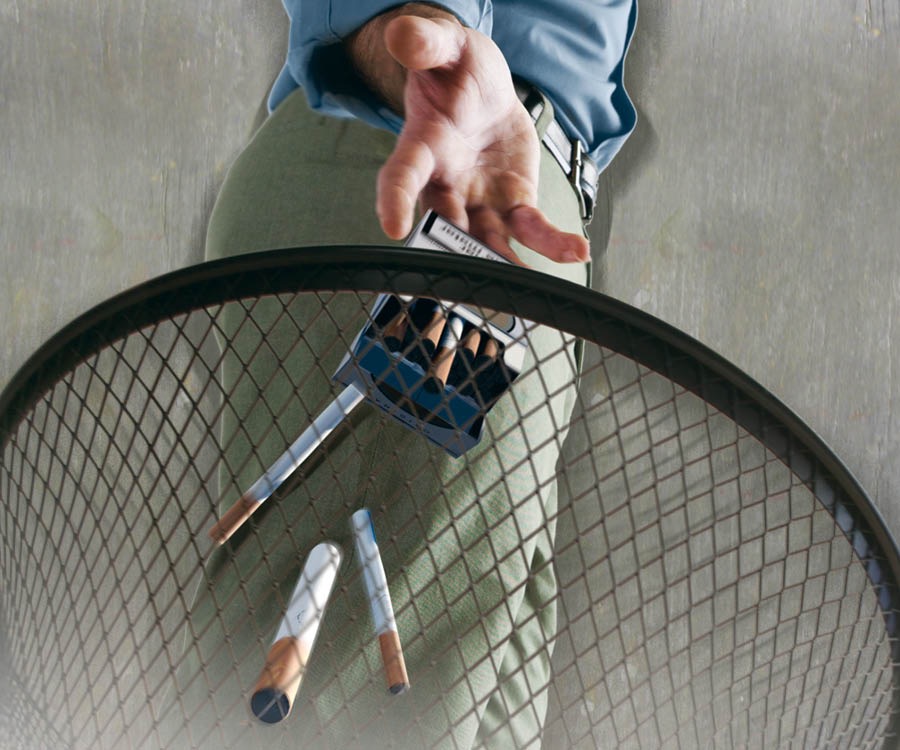 Um homem joga cigarros no lixo