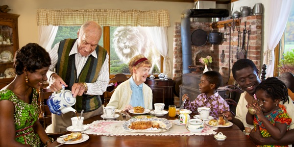 Pessoas de diferentes idades e raças comendo juntas; desenho de um leão furioso olhando pela janela