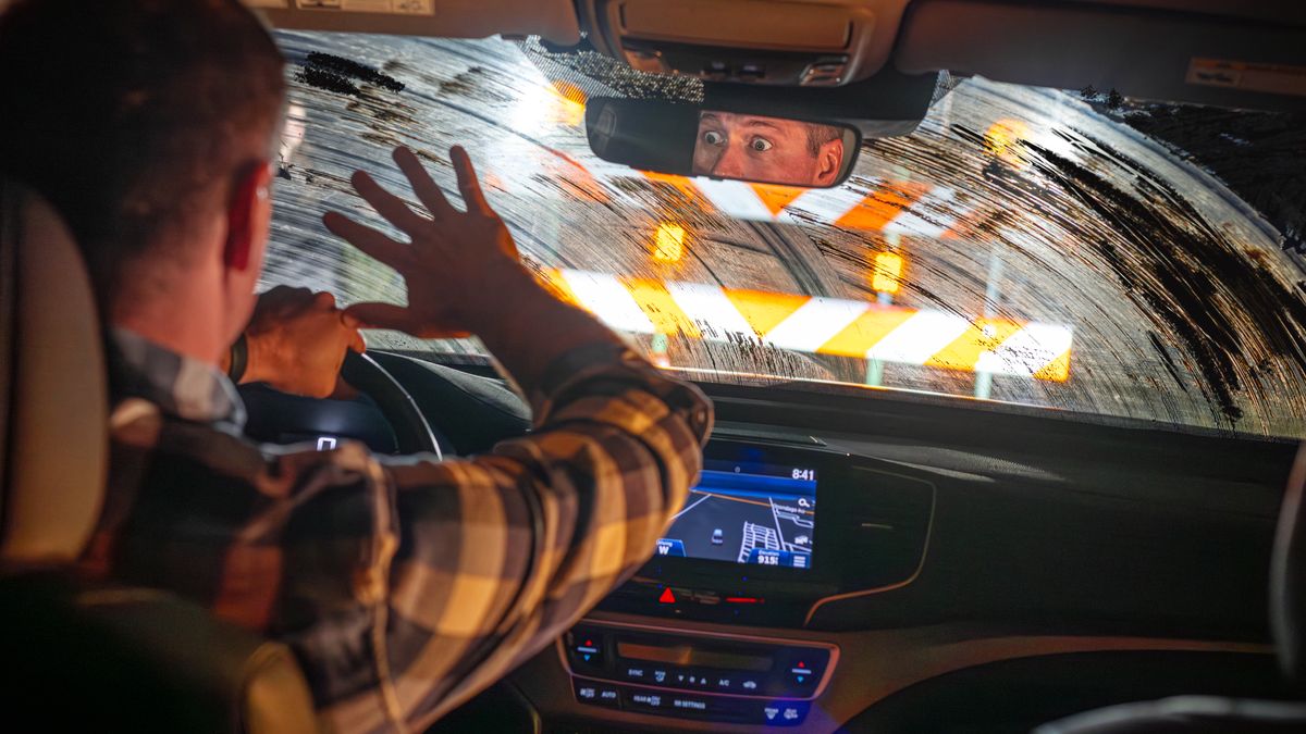 Um homem dirigindo um carro com o para-brisa sujo encontra de repente uma barreira rodoviária bem na frente dele.