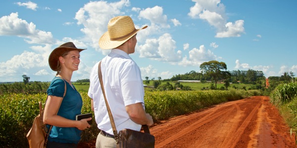 Um casal cristão caminhando por uma estrada longa de terra para ir pregar
