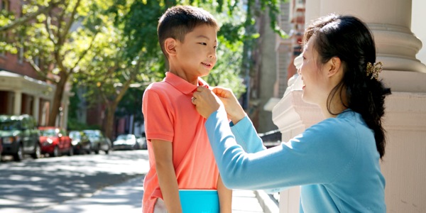 A mother buttoning her young son’s shirt
