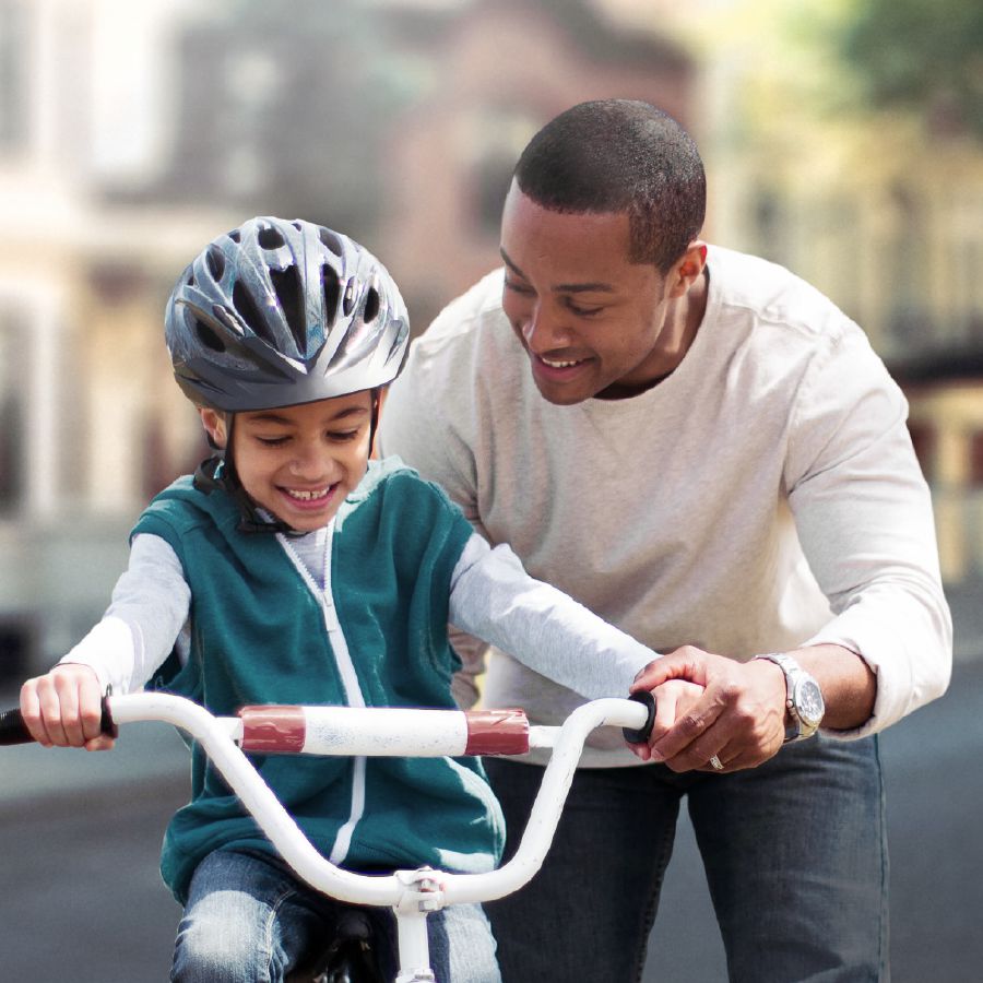 Un tată își învață fiul să meargă pe bicicletă