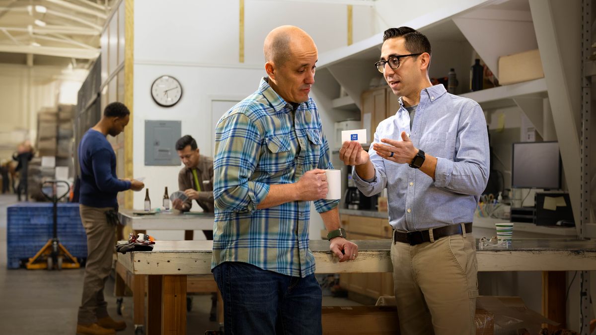 Во время перерыва брат рассказывает коллеге о сайте jw.org и даёт ему визитную карточку.