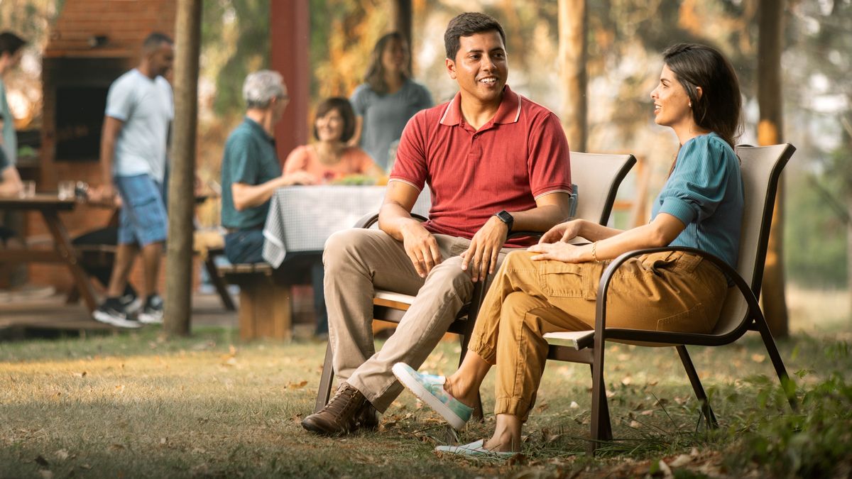 На дружеской встрече брат и сестра, которые встречаются, сидят рядом в креслах и оживлённо разговаривают. Позади них, чуть поодаль, общаются друг с другом остальные братья и сёстры.