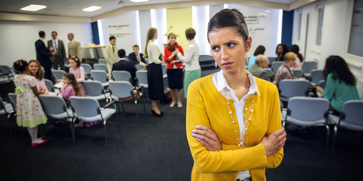 Nezadovoljna sestra v kraljestveni dvorani s prekrižanimi rokami stoji stran od drugih.