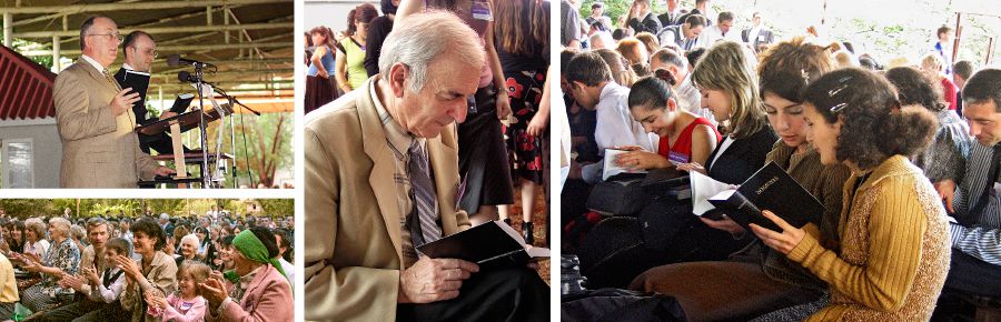 Navzoči ploskajo, ko Geoffrey Jackson objavi izid Prevoda novi svet v gruzinščini; Priče skrbno pregledujejo novo Biblijo.