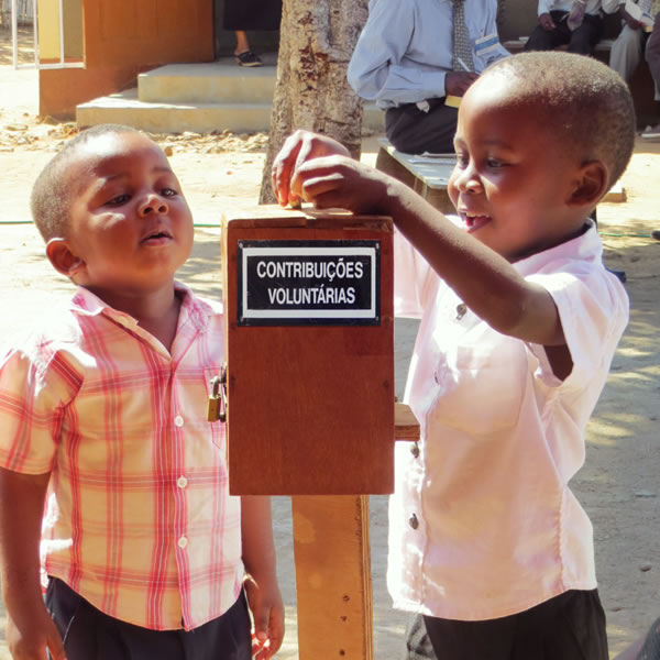 Vijana wawili wadogo wakitumbukiza pesa katika sanduku la michango