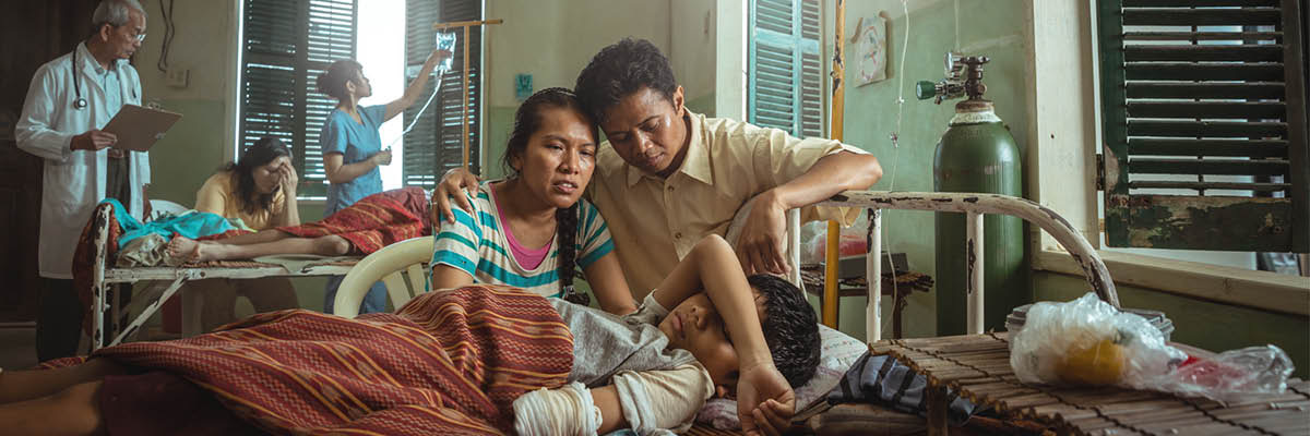 พ่อ​แม่​ที่​กำลัง​กังวล​นั่ง​อยู่​ข้าง ๆ เตียง​ลูก​ของ​พวก​เขา​ใน​โรง​พยาบาล