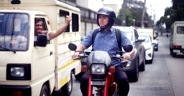 Wanpela man i draivim kar i belhat na singaut long Cassius, tasol em i stap isi na ronim motobaik
