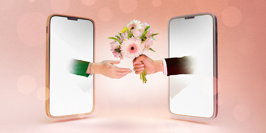 دو موبائل سکرین جن میں سے ایک سکرین سے آدمی کا ہاتھ پھول دینے کے لیے باہر نکل رہا ہے اور دوسری سکرین سے ایک عورت کا ہاتھ پھولوں کو پکڑنے کے لیے باہر نکل رہا ہے۔‏